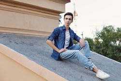 Male teenager in denim sitting on roof