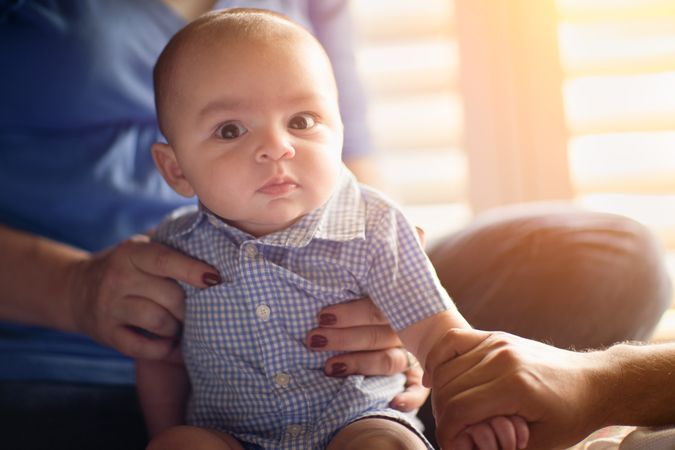 Happy Couple Enjoying Their Newborn Son In The Light of The Window.