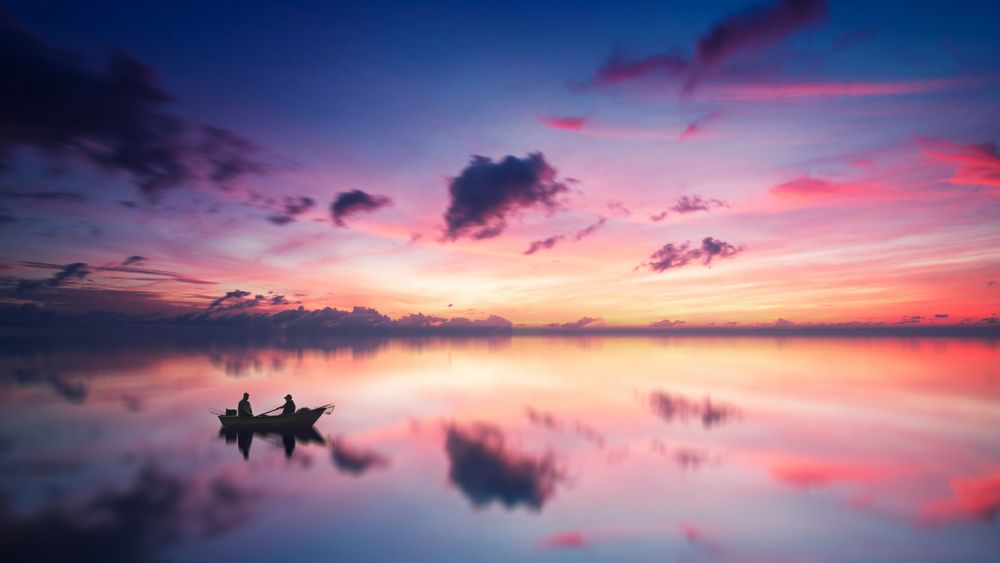 Silhouette of two people on boat during sunset