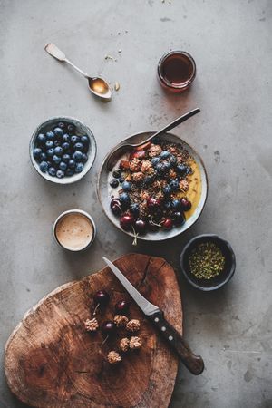 Oat granola yogurt bowl with cherries, blueberries, honey, nuts, coffee, wooden board