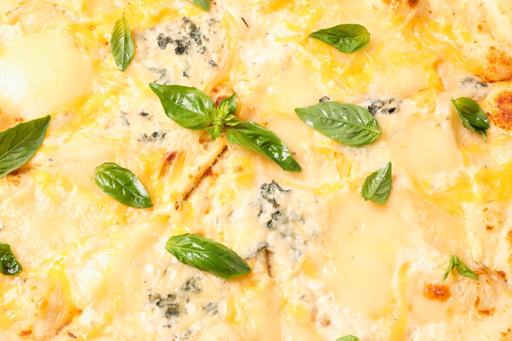 Tasty cheese pizza with basil on whole background, closeup