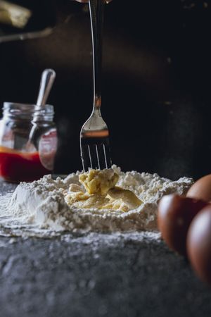 Cook preparing dough with egg and flour