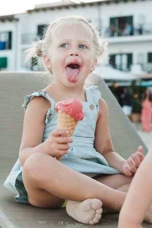 Cute girl eating ice cream cone on sunbed
