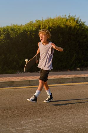 Expressive skater walking with skateboard along road