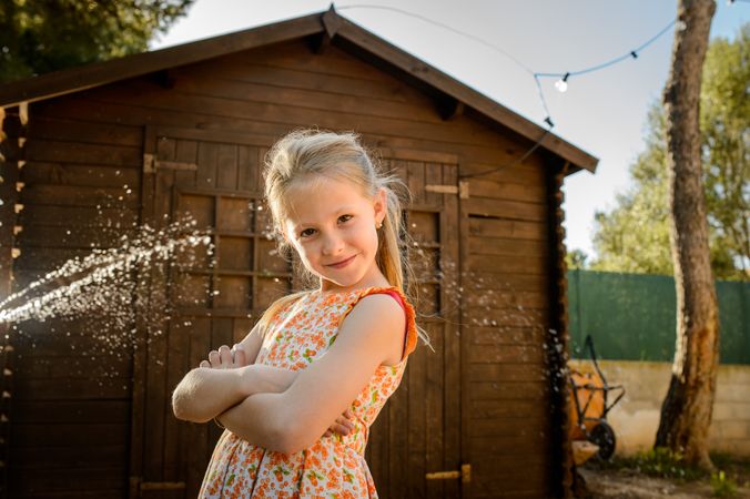 Girl with folded arms against barn in countryside