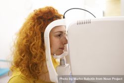 Red haired woman in machine in optometrist office 49QPy4