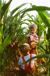 Cute little brother playing together in green corn field