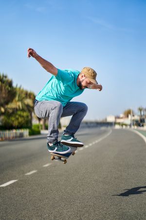 a man doing an ollie with his skateboard on an asphalt road next to the harbor