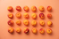 Many apricots organized neatly on an orange background