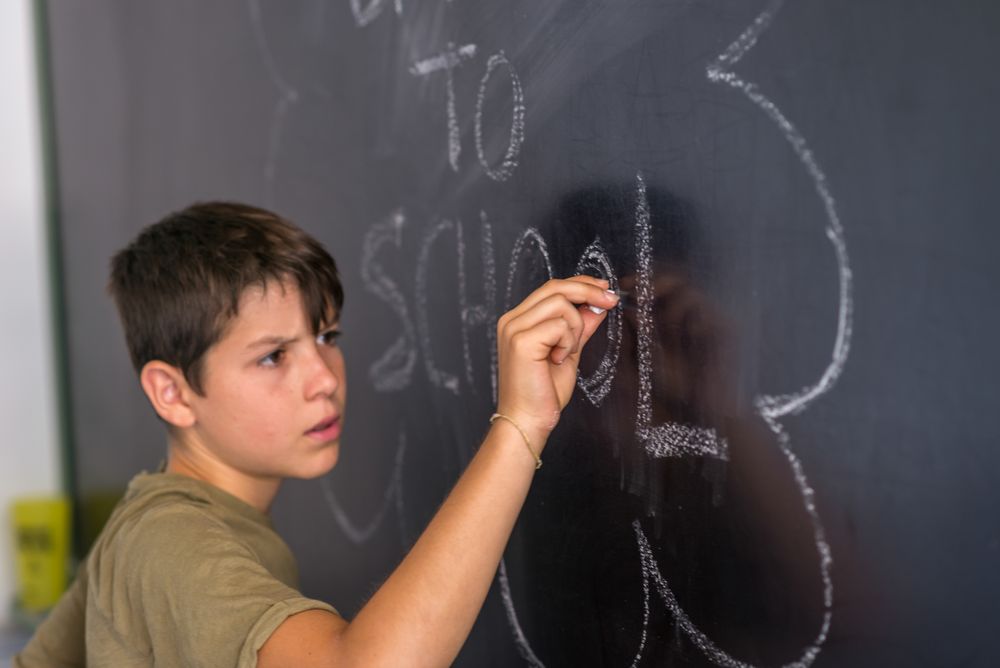 Boy writing on chalkboard