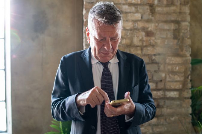 Mature businessman texting on smartphone
