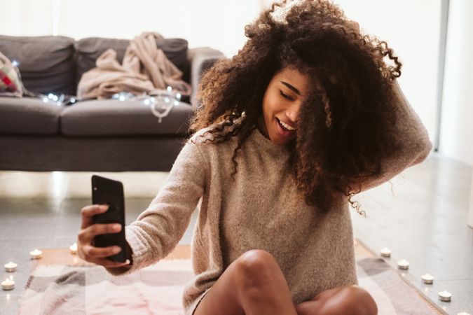 Black woman taking selfie on floor