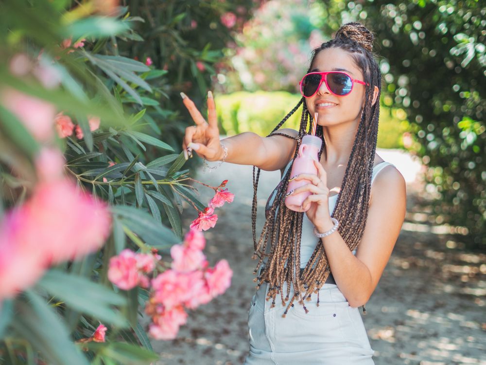 Stylish young woman with dreadlocks and beverage