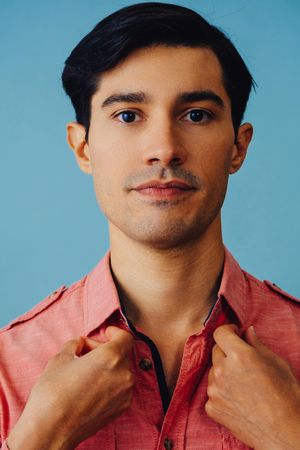 Portrait of serious Hispanic male fixing his shirt, vertical