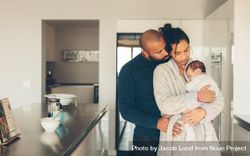 Young father and mother holding their baby boy in kitchen 0vR8g0