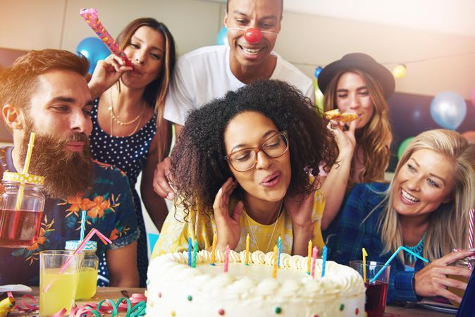 Close up of faces as woman blows out birthday candles