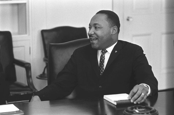 A smiling Martin Luther King, Jr participates in a meeting in the Cabinet Room