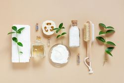 Relaxing bath salts and oils, loofah and brushes on beige with green branches