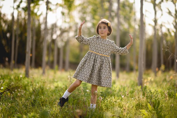 Surprised child standing in dress in nature surrounded by trees
