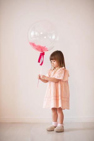 Studio shot of girl in pink dress holding standing