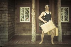 Gentleman Dressed in 1920’s Era Swimsuit Holding Suitcases on Porch