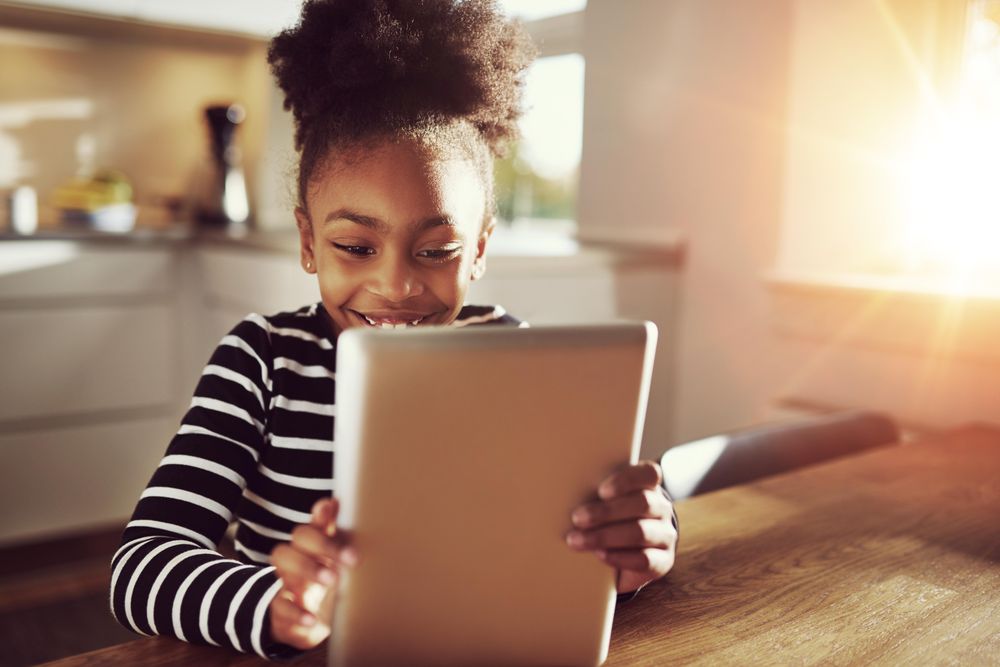 Shot of happy girl using tablet in sunny room
