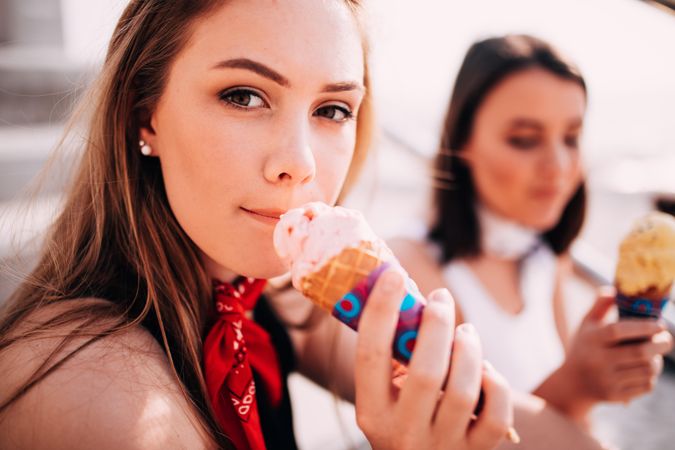 Young woman holding an ice cream cone making eye contact with the viewer