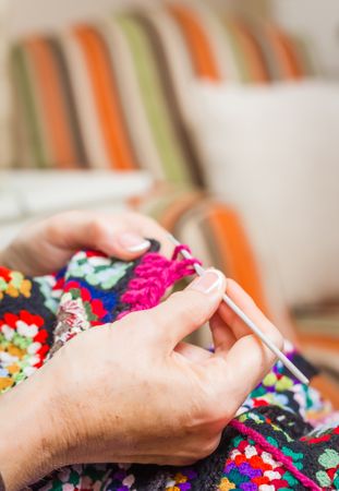 Hands of woman knitting a vintage wool quilt