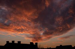 Dark pink clouds over a home at sunset