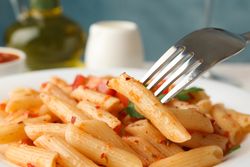 Composition with plate of tasty pasta and fork, close up