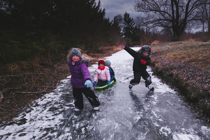 Children playing on frozen stream in the woods