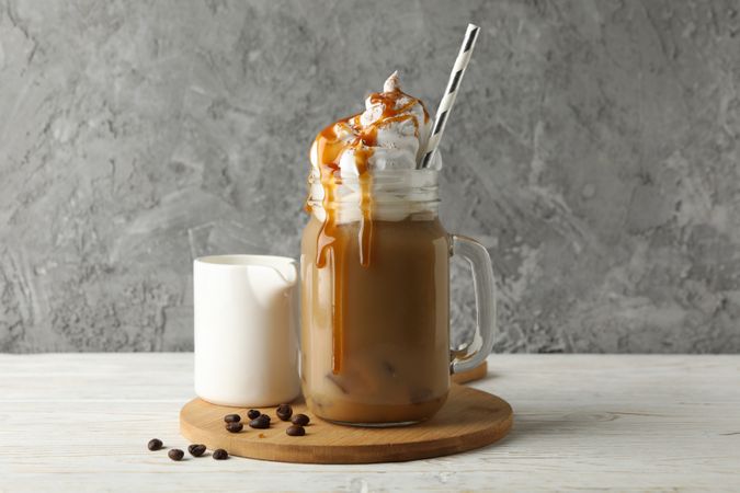 Iced coffee with poured cream on wooden background