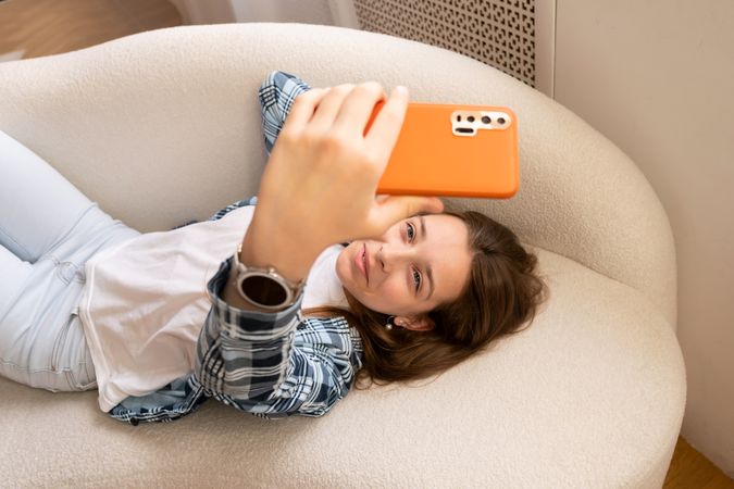 Close-up of smiling teenage girl taking smartphone selfie.