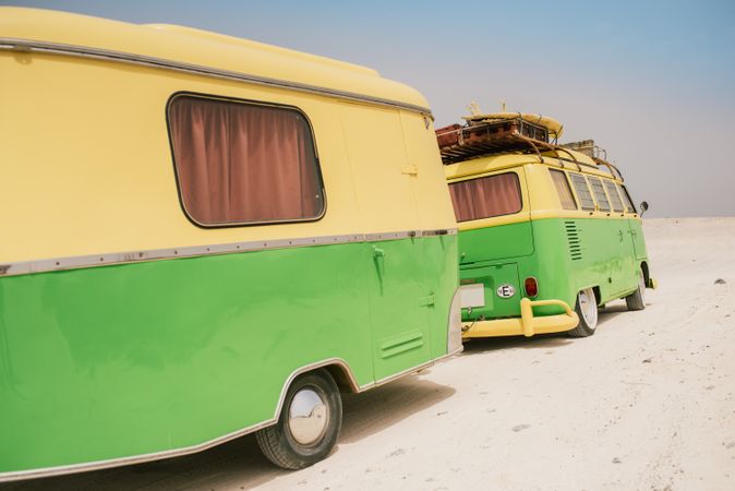 Colorful minibus with trailer parked on sandy shore in sunny day