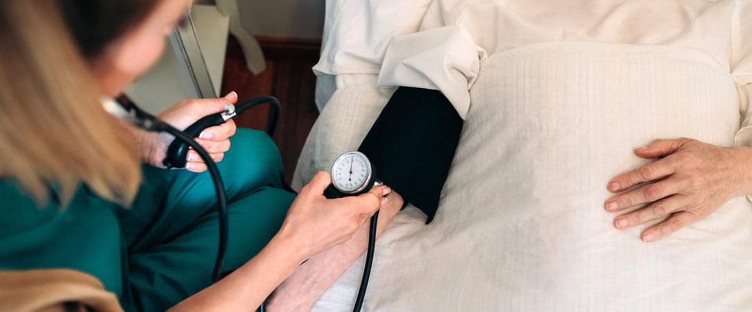 Caregiver checking blood pressure to a mature woman