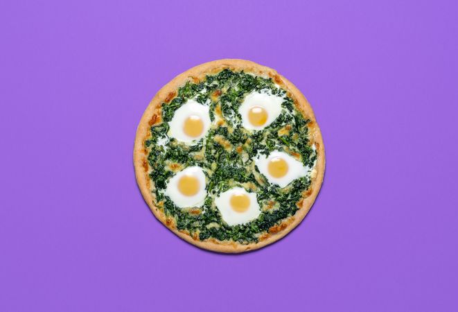 Vegetarian pizza with spinach and eggs isolated on purple color