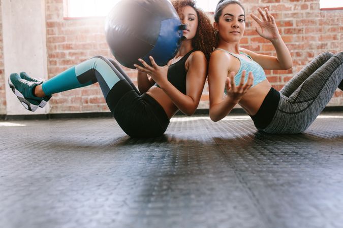 Two sporty women training with medicine ball in gym