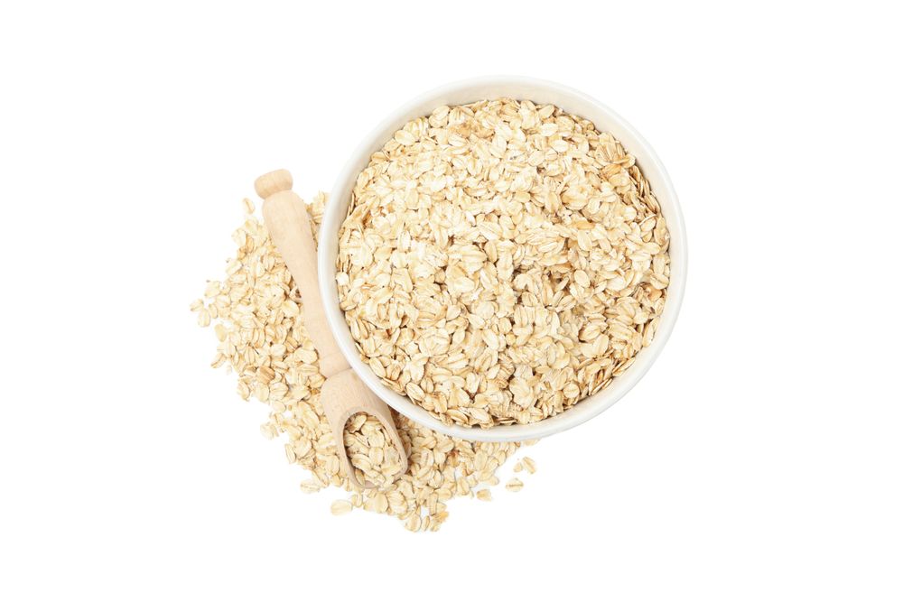 Bowl and scoop with oatmeal flakes isolated on plain background