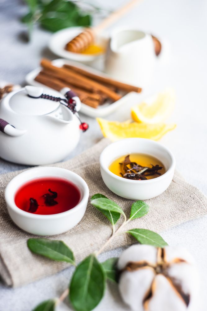 Two delicate cups of tea with tea pot in background