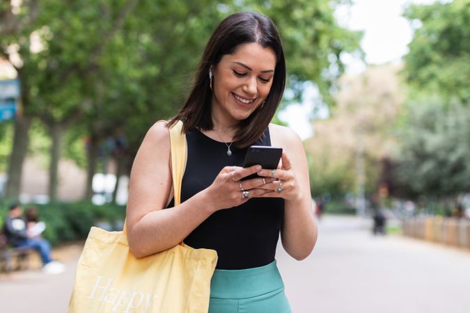 Smiling woman messaging on smartphone in city