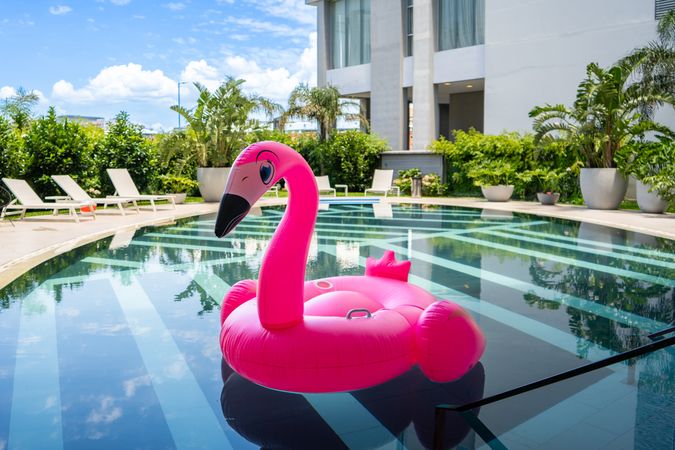 A pink flamingo pool float is floating in a pool.