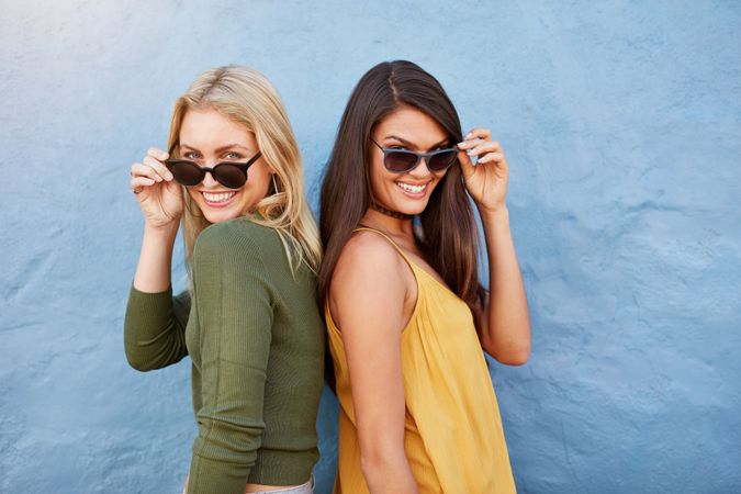 Attractive young woman friends wearing sunglasses and smiling into camera