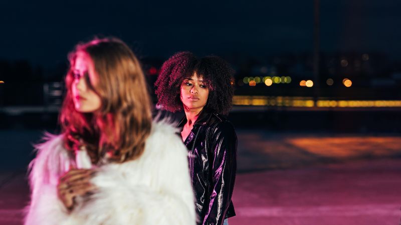 Two trendy woman standing in moody red light at night