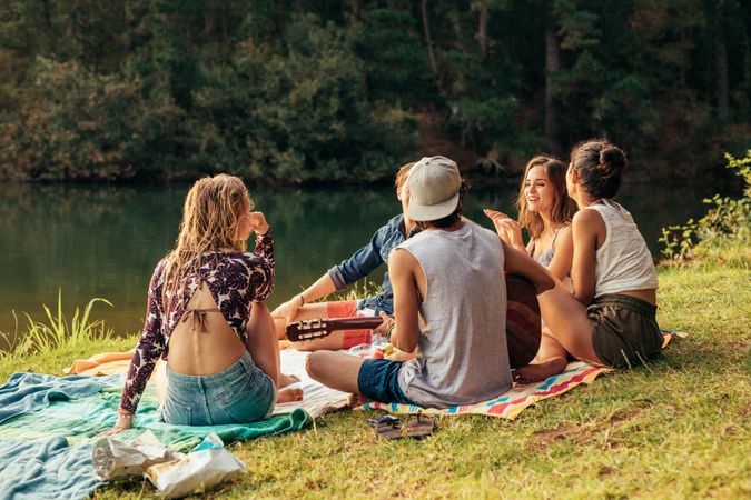 Group of young people having picnic near a lake