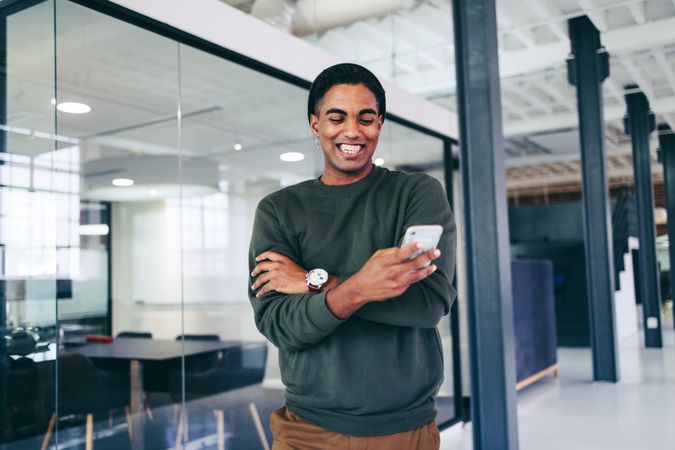 Happy young businessman smiling cheerfully while reading a text message in