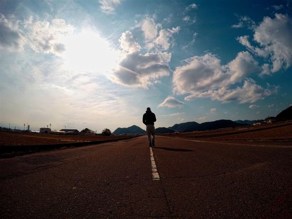 Back view of a man walking in the middle of the road