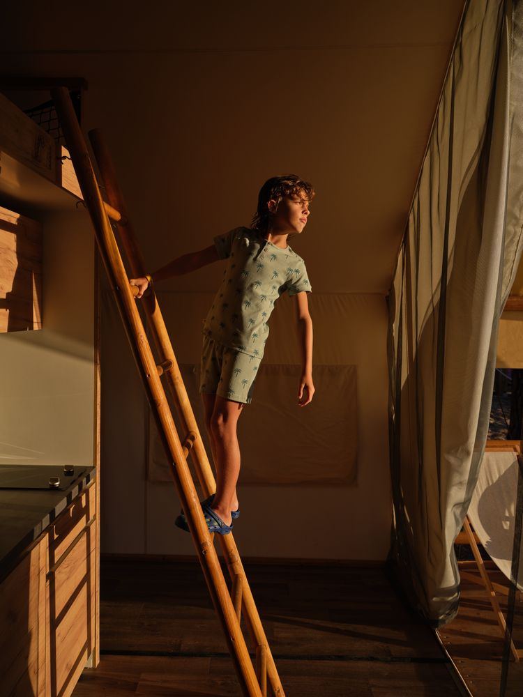 Boy in sleepwear standing on wooden ladder