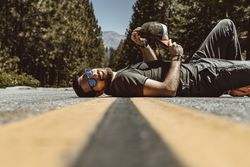 Cheerful man resting on asphalt rural road