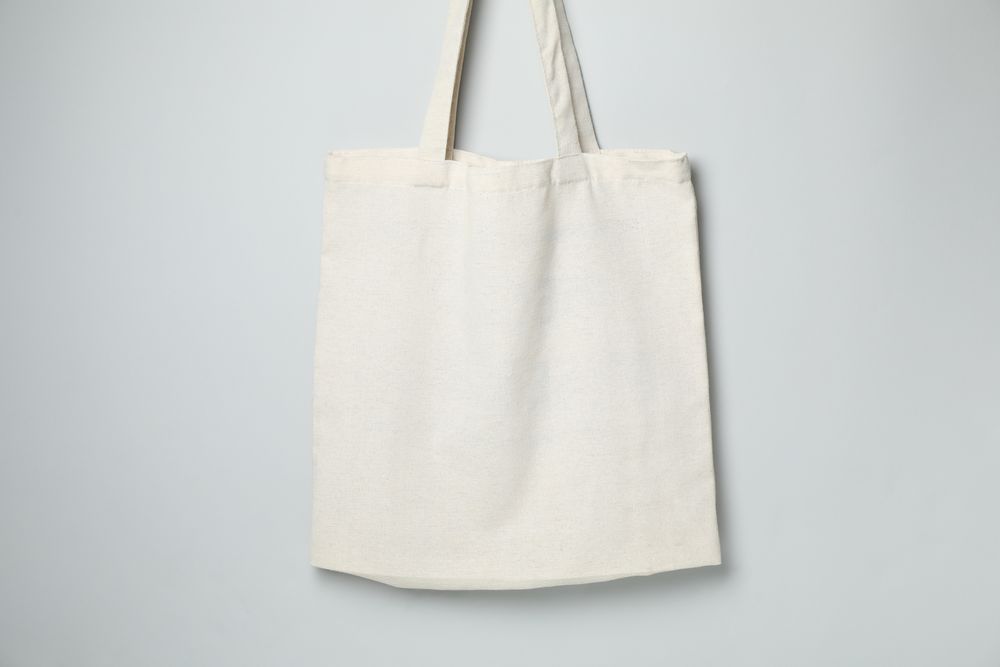 Empty light canvas bags on gray background, space for text.