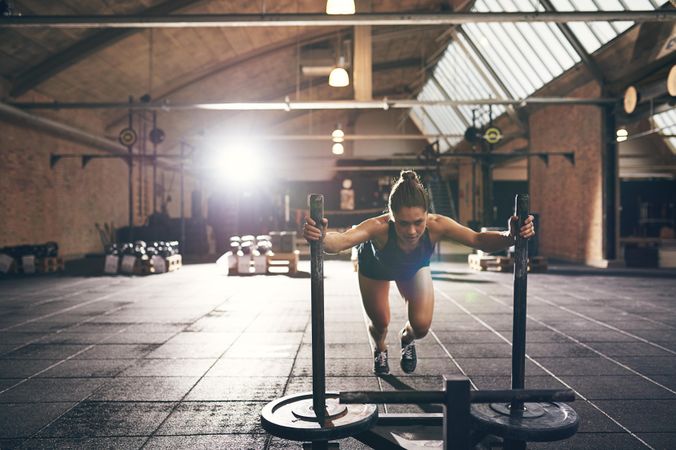 Woman with serious expression pushing weighted sled